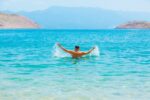 A man swimming in a lake with mountains in the background