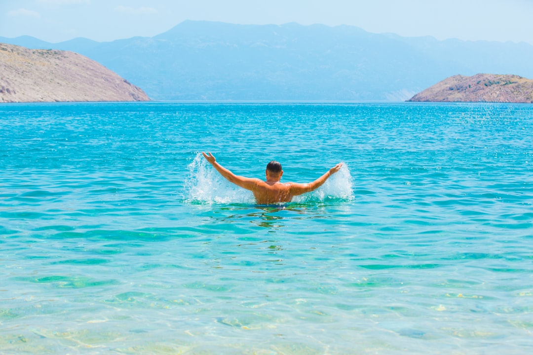 A man swimming in a lake with mountains in the background