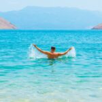 A man swimming in a lake with mountains in the background