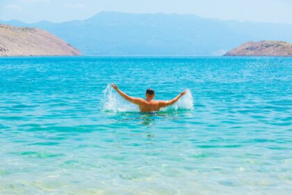A man swimming in a lake with mountains in the background