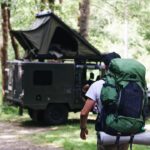 Rucksack mit ausgerolltem Packsystem, bestehend aus wasserdichten Trockensäcken, Kabel-Organizer, Powerbank und kompaktem Outdoor-Equipment.