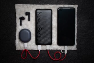 Eine schwarze Powerbank mit mehreren Kabeln liegt neben Gitarreneffektpedalen auf einer Holzbank.