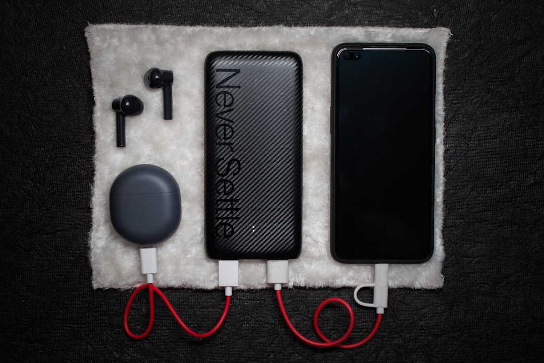 Eine schwarze Powerbank mit mehreren Kabeln liegt neben Gitarreneffektpedalen auf einer Holzbank.