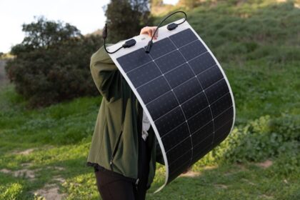 Faltbares Solarmodul ausgebreitet auf einem Campingtisch, daneben ein aufgeladenes Smartphone und eine Powerbank.