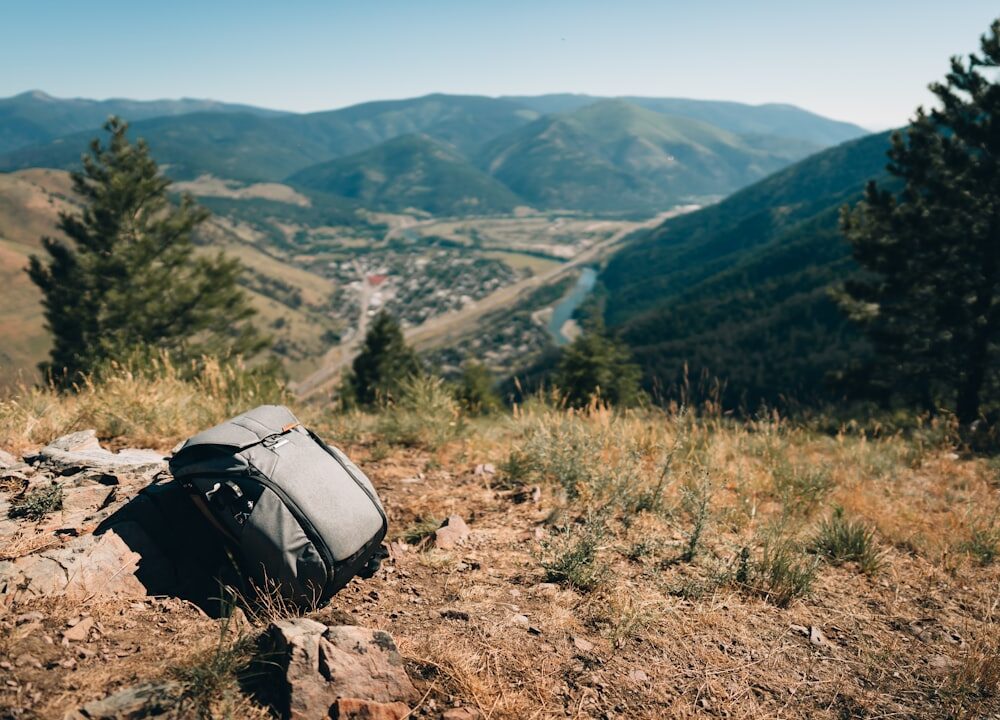 Peak Design Everyday Sling 3L V3 in Schwarz, um die Schulter getragen, mit geöffnetem Hauptfach und einem schnell erreichbaren Smartphone.