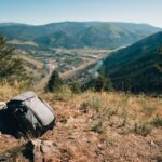 Peak Design Everyday Sling 3L V3 in Schwarz, um die Schulter getragen, mit geöffnetem Hauptfach und einem schnell erreichbaren Smartphone.