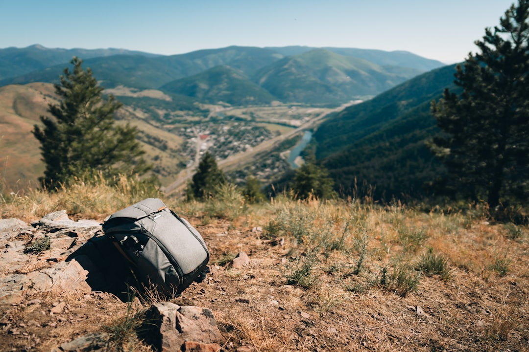 Peak Design Everyday Sling 3L V3 in Schwarz, um die Schulter getragen, mit geöffnetem Hauptfach und einem schnell erreichbaren Smartphone.